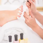 close-up-pedicurist-applying-nail-polish-toenails